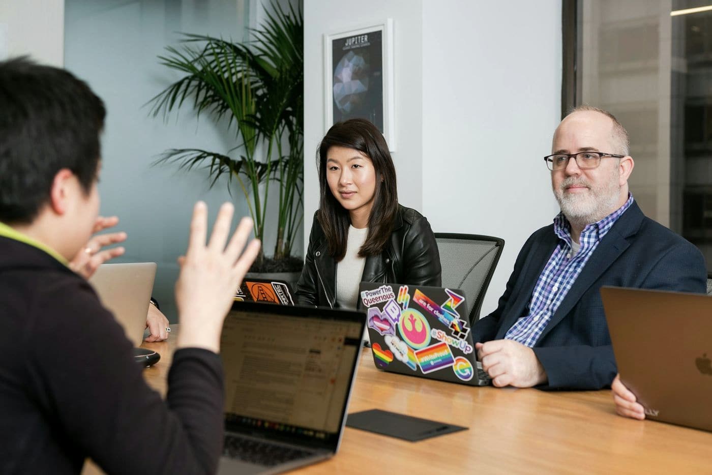 Investors discussing a deal around a meeting table with laptops