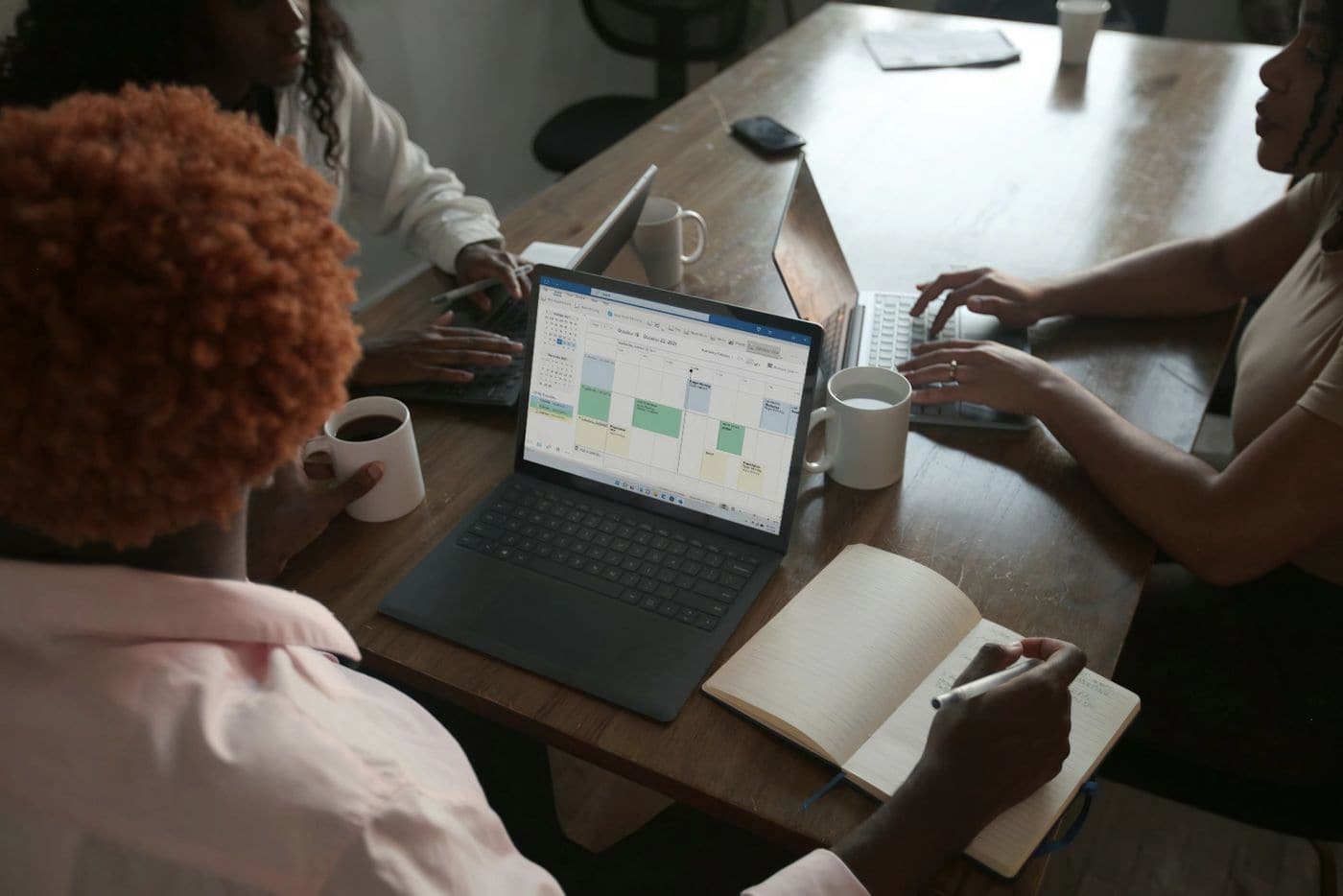 A deal team working on laptops around a wooden table